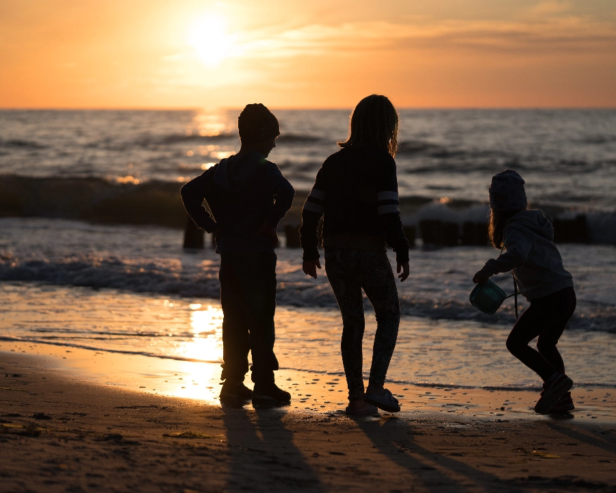 mother with two children on the beach as the sun begins to set.