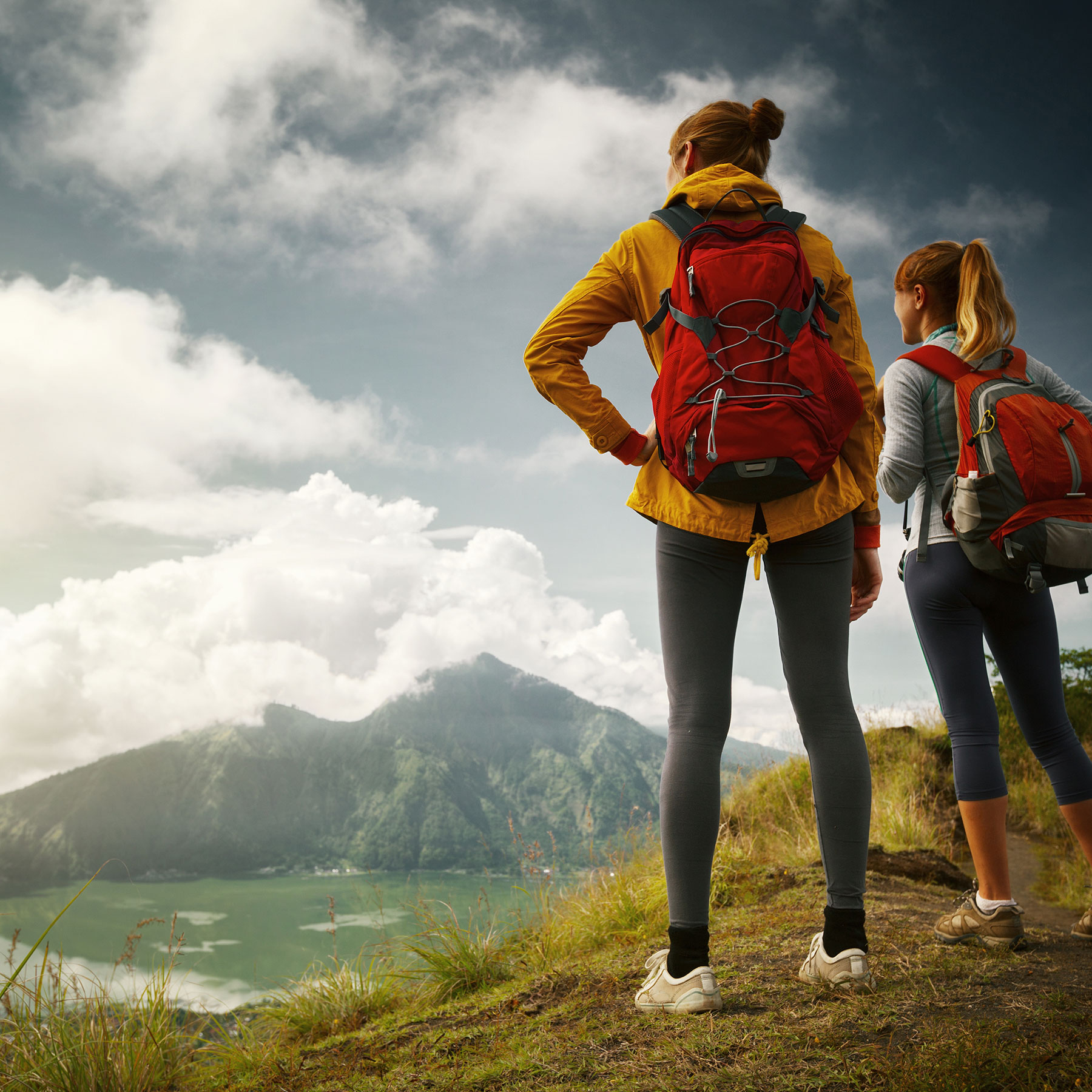 Two eager gals plan their next move around a mountain lake in the afternoon hiking.