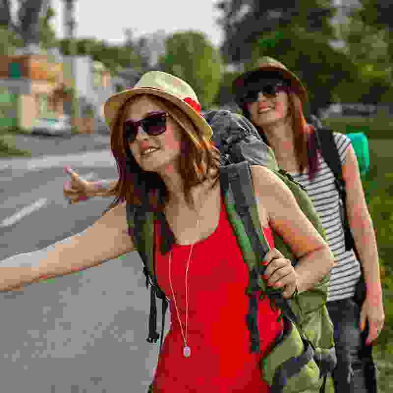 Two women hitchhiking with backpacks.