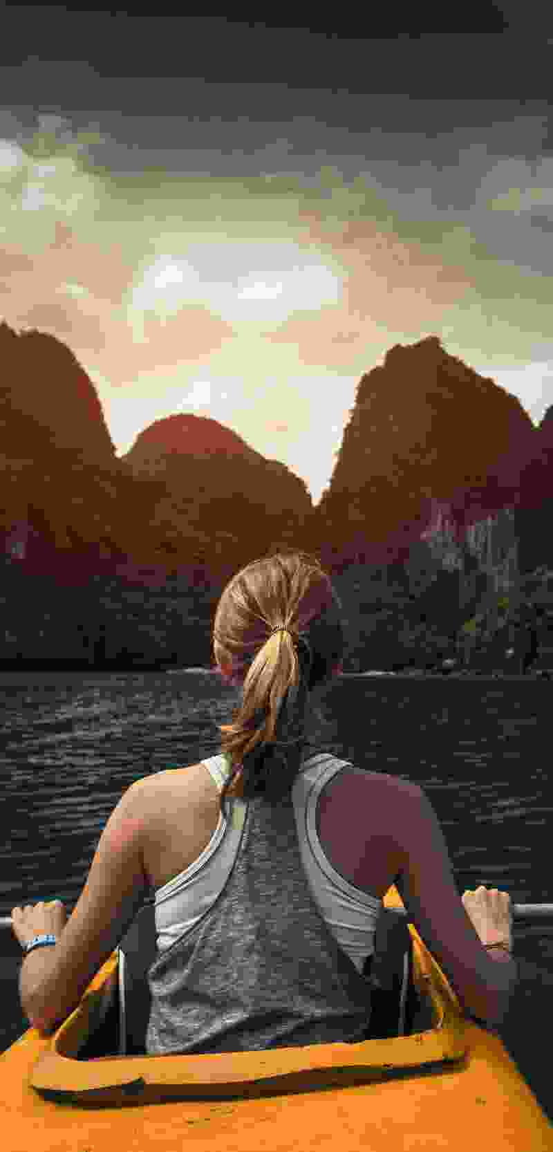 Attentive Western woman stops her kayak to ponder a large rock formation close ahead.