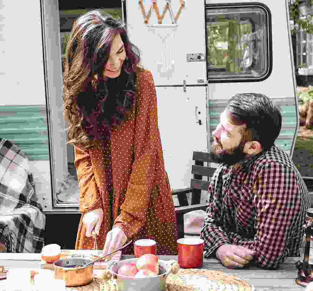 Traveling couple cooks breakfast outside their RV.