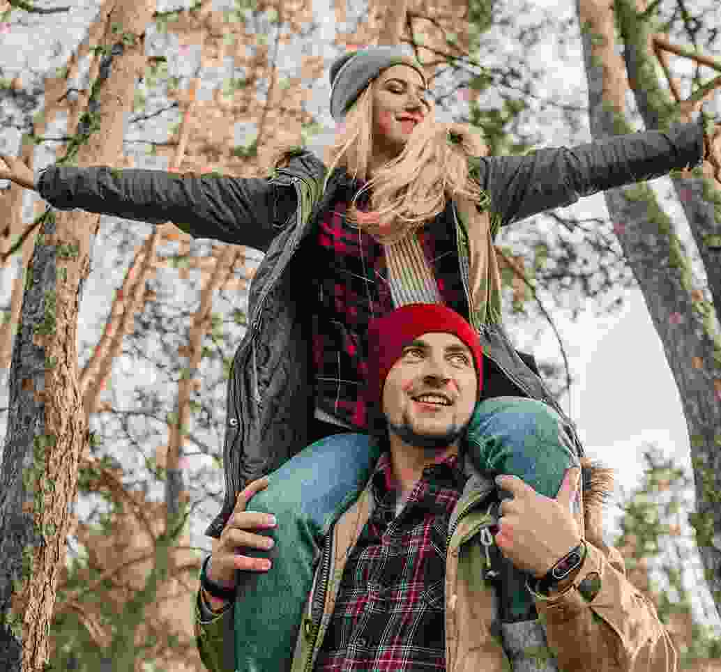 Expressive Western couple display their affection while hiking through the woods.