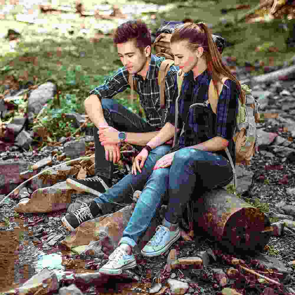 Young man sits on a log with a young woman and struggles to find the courage to tell her how he feels.