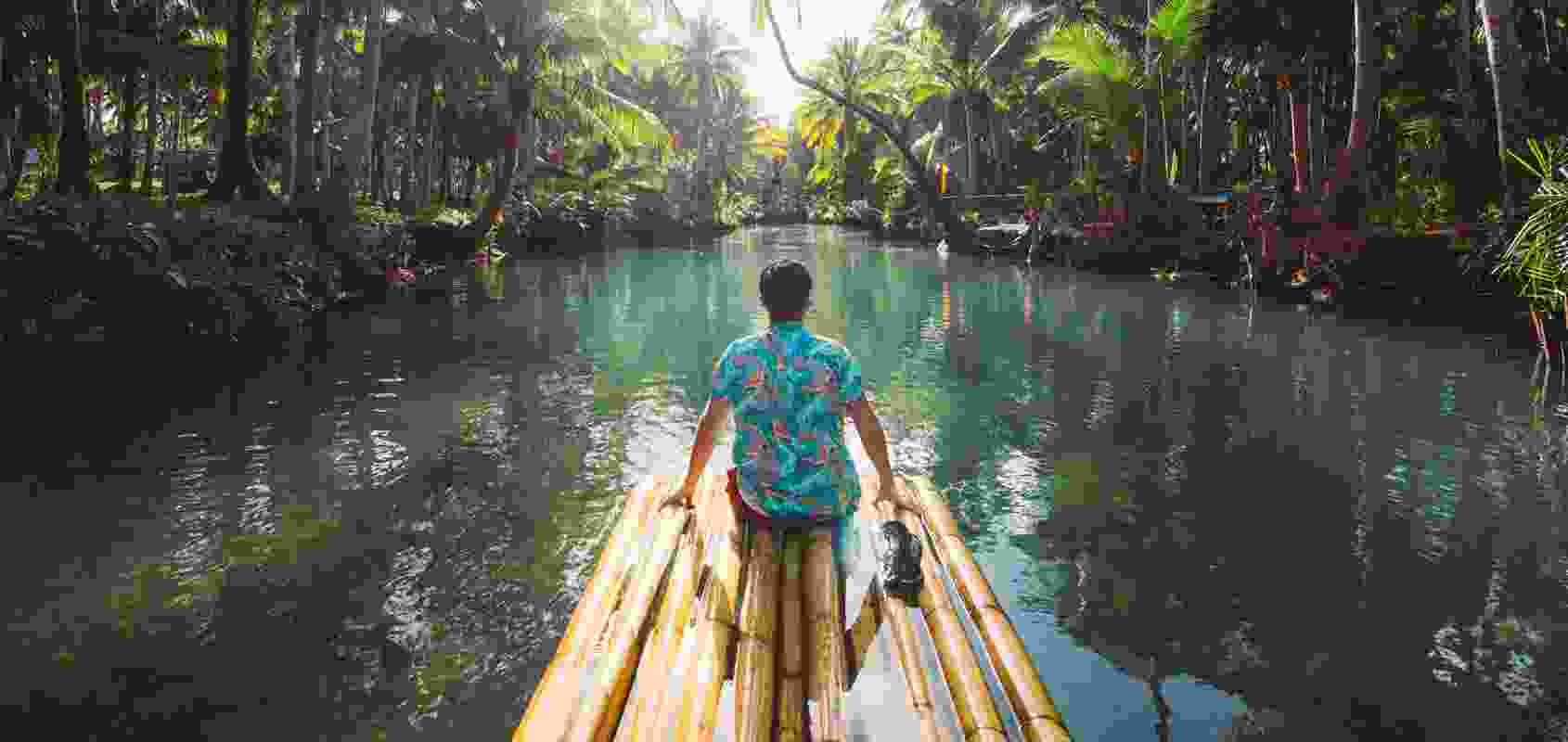 A man on a bamboo dock getting dangerously close to crocodile infested waters.